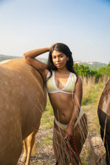 Woman in a yellow and ivory bikini set standing next to a horse with a scenic background
