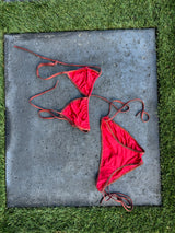 Red bikini set on a concrete slab with grass background