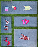 Colorful swimwear and bags arranged on a tiled ground with turf.