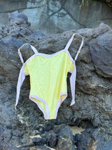 Yellow swimsuit with white straps on a rocky surface